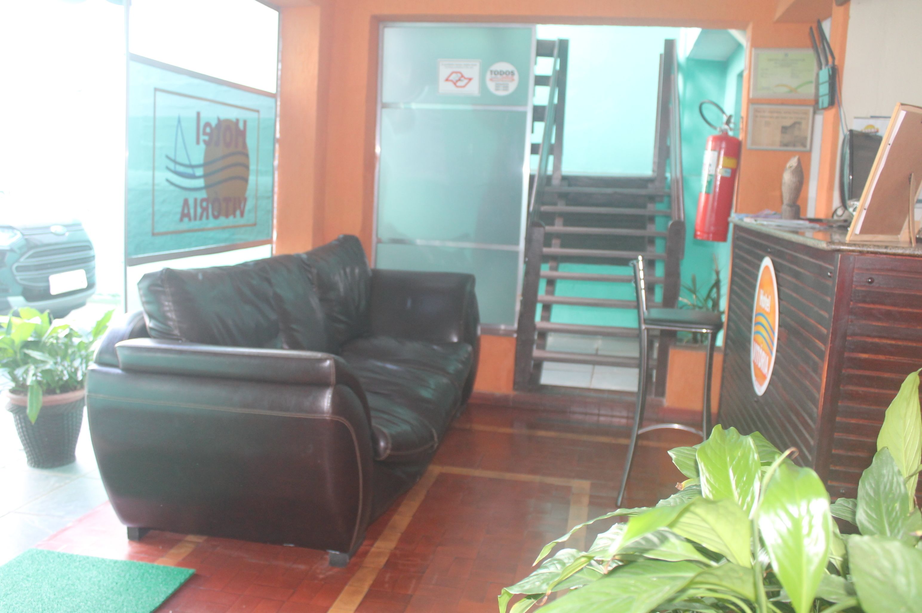 A room with a leather sofa, a wooden cabinet, and a green mat on the floor.