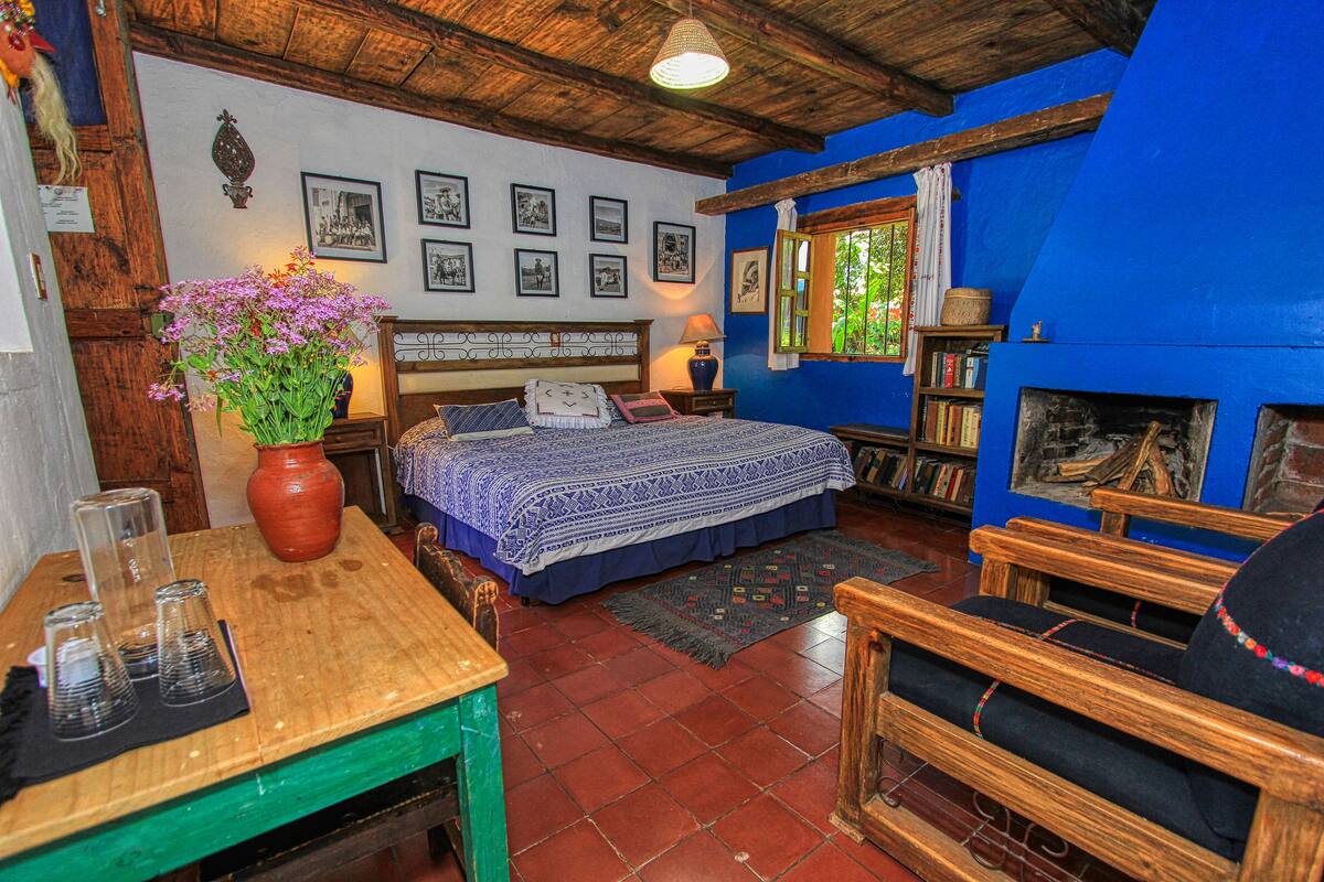 A room with a bed, wooden furniture, a fireplace, and a bookshelf.