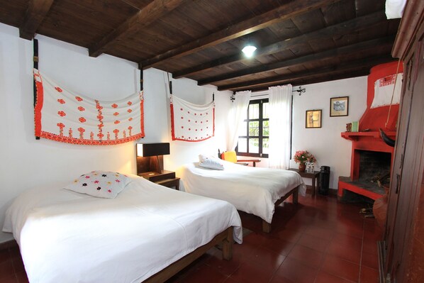 A room with two beds, a fireplace, and a window with curtains.