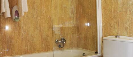 A bathroom with a bathtub, toilet, and a glass-enclosed shower.
