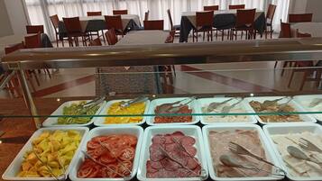 A buffet with various food items and a dining area with chairs and tables.