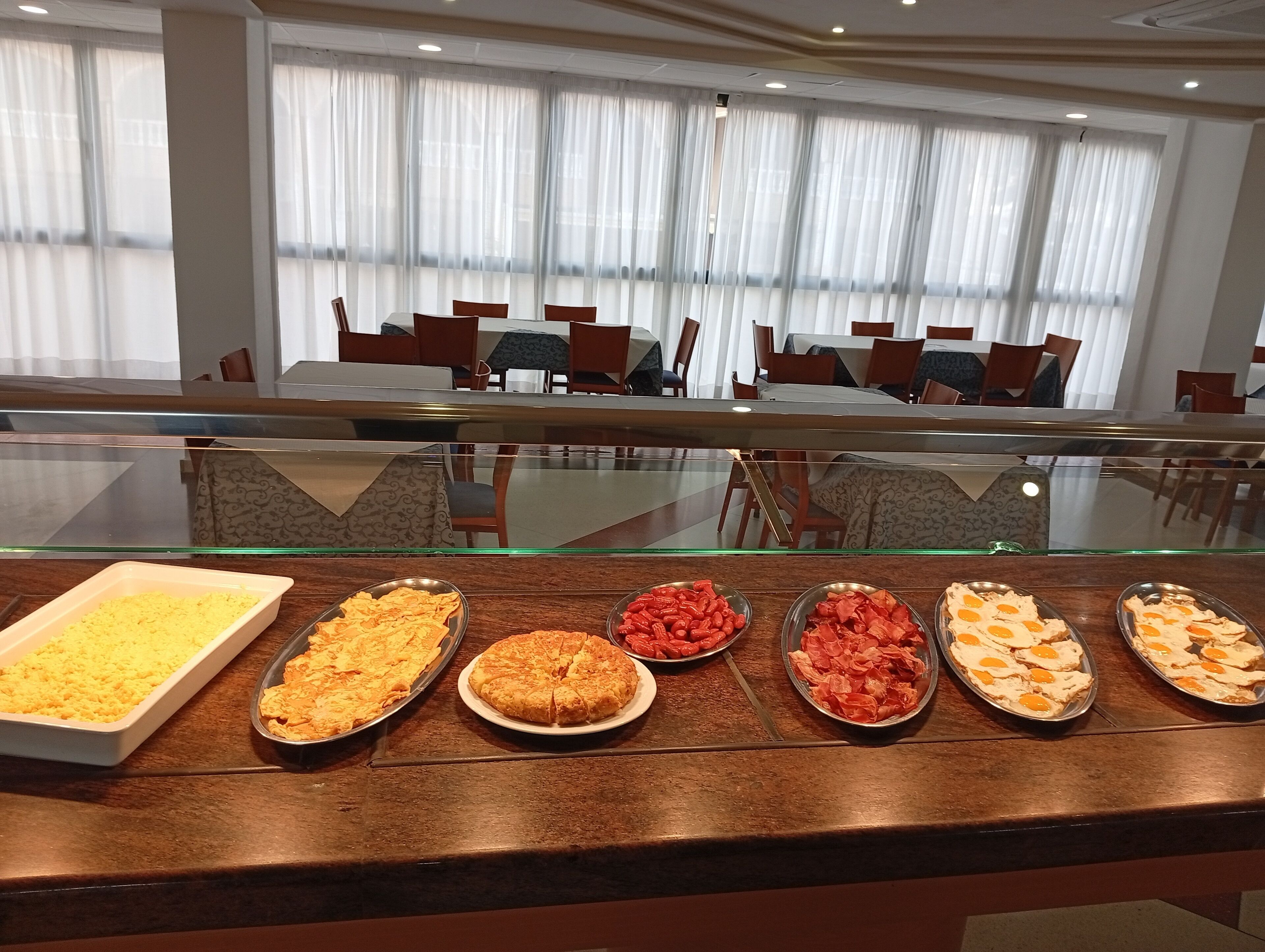 Ein Buffet mit verschiedenen Speisen, darunter eine Schale gelber Reis, ein Teller Kekse und mehrere Gerichte mit roten Bohnen und Orangenscheiben.
