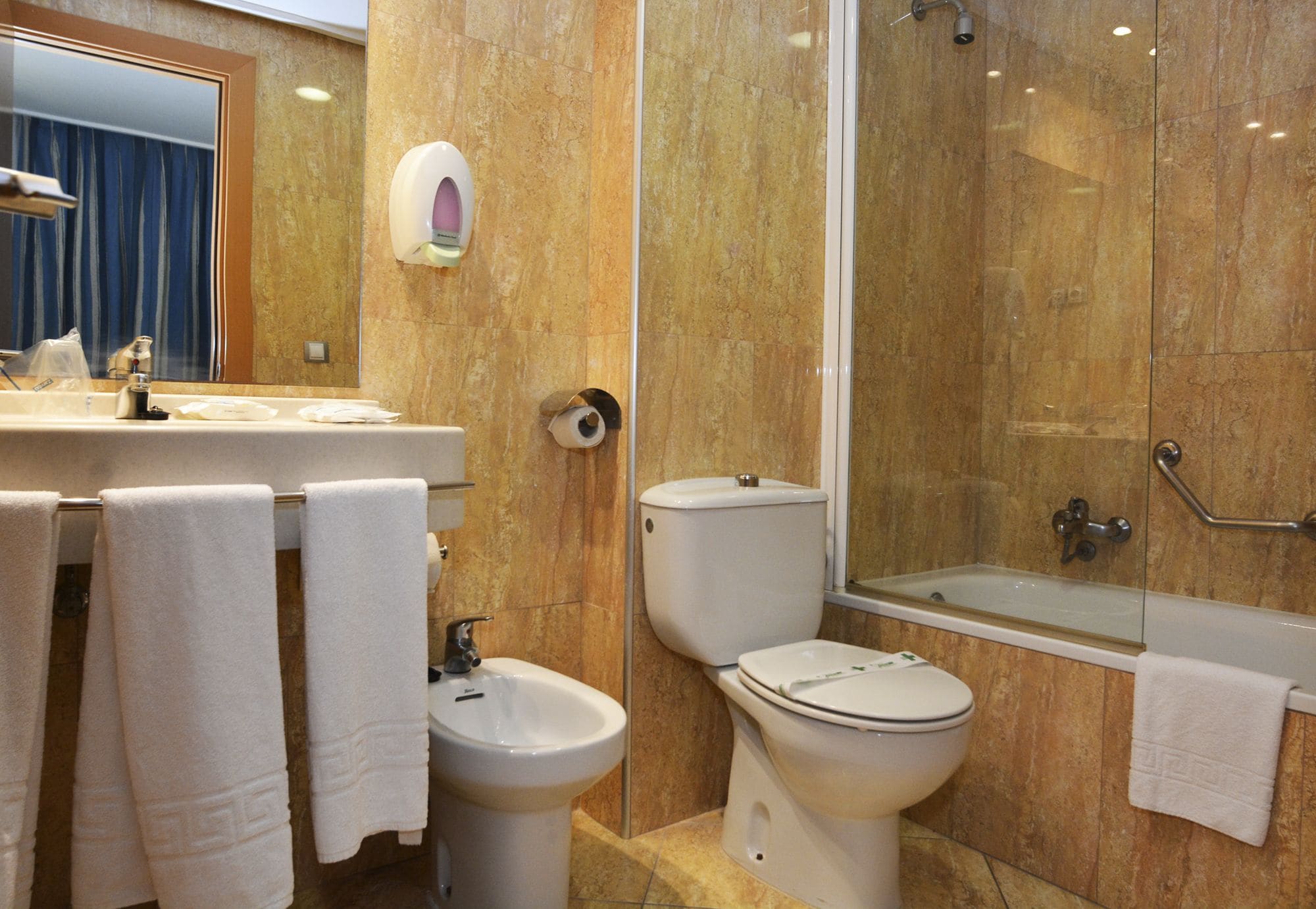 A bathroom with a sink, bidet, toilet, and bathtub.