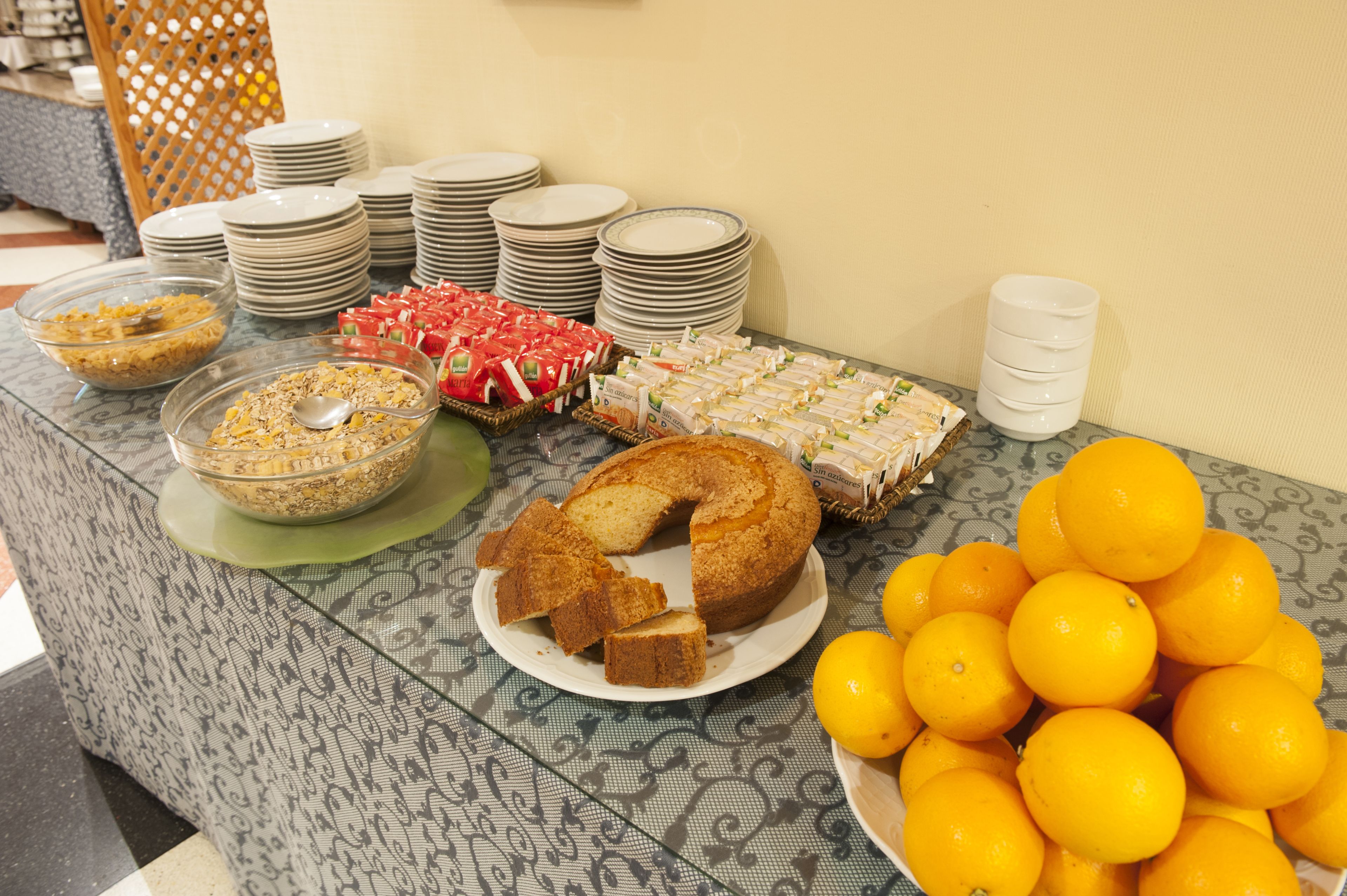 Una mesa de buffet con diversos alimentos, como pastel, sándwiches y naranjas.