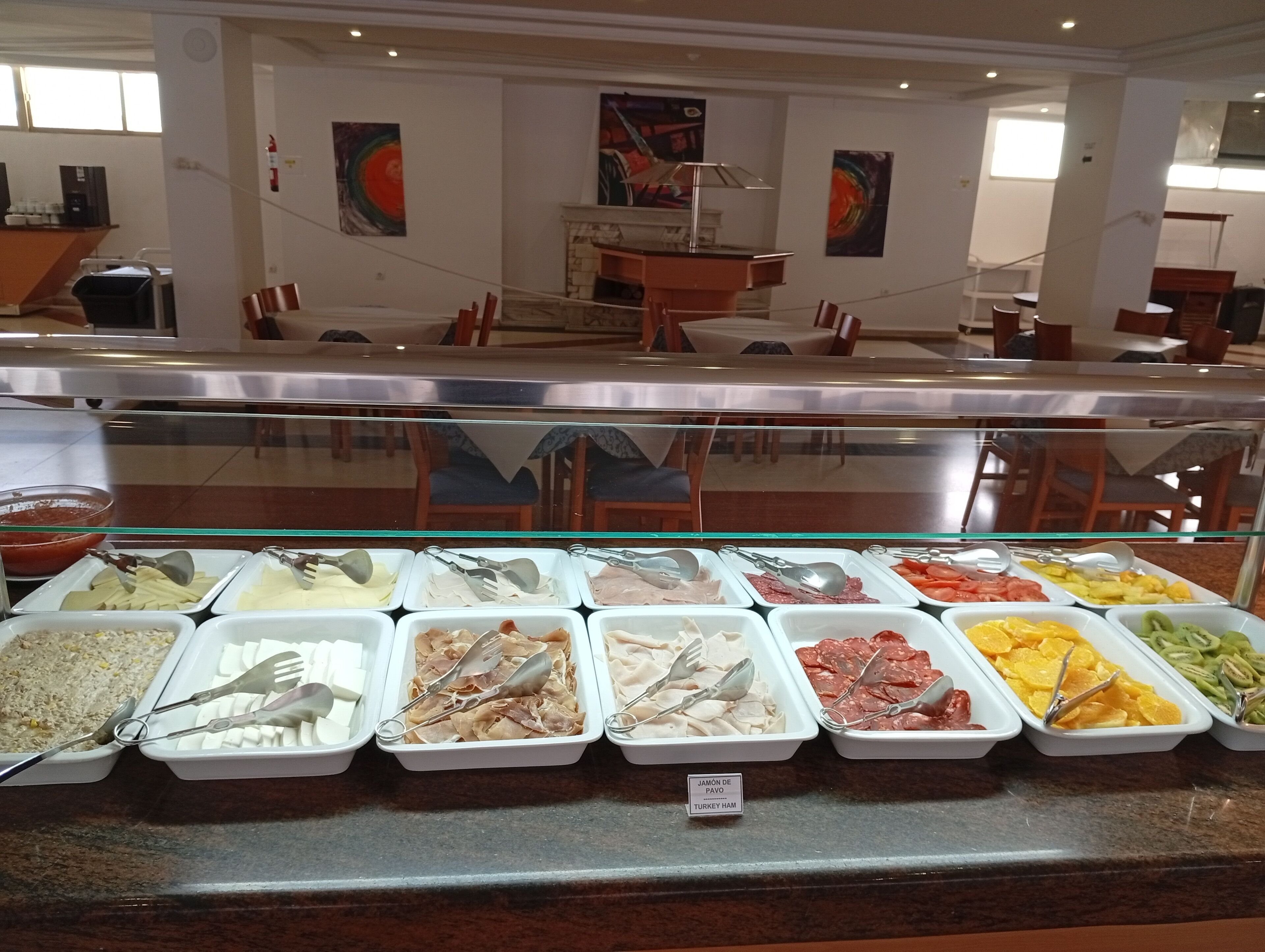 Un bufé con diversas opciones de comida, entre ellas carnes, quesos y frutas.