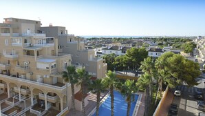 A multi-story hotel with balconies, a swimming pool, and palm trees. - Hotel Torrejoven (Torrevieja)