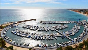 A marina with boats docked in a circular layout, surrounded by a waterfront promenade. - Hotel Torrejoven (Torrevieja)
