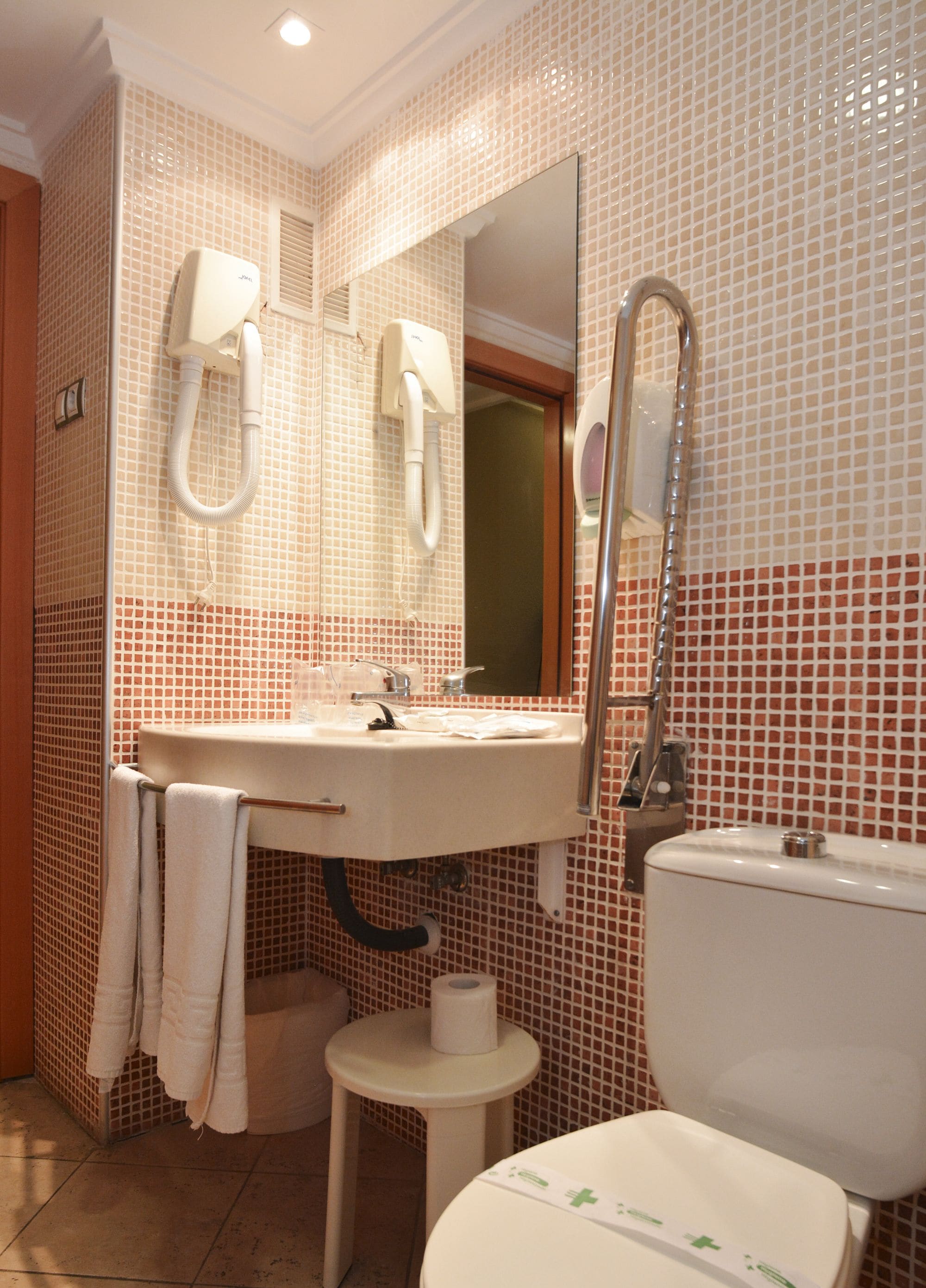 Een badkamer met een wastafel, spiegel, toilet en handdoekhouder.