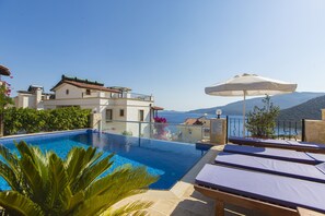 Una piscina con borde infinito, una piscina climatizada, tumbonas