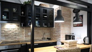 Una cucina moderna con mobili neri, un piano di lavoro in legno, forno integrato, lavello e lampada a sospensione.