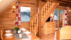 Une cabane en bois comprenant un coin repas, un escalier et un lit.