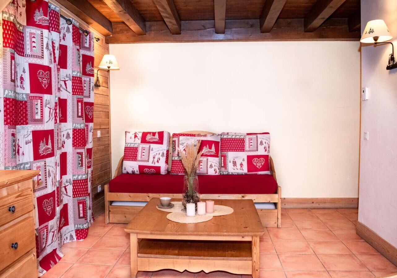 A cozy room with a wooden bench, a small table with candles, and a wall with a red and white patterned quilt.