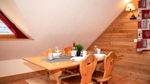 Un coin repas avec une table en bois mise pour quatre personnes, comprenant des verres à vin, des assiettes et une bougie.