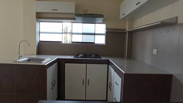 Een koelkast, kookgerei, borden en bestek, keukenpapier, een eettafel