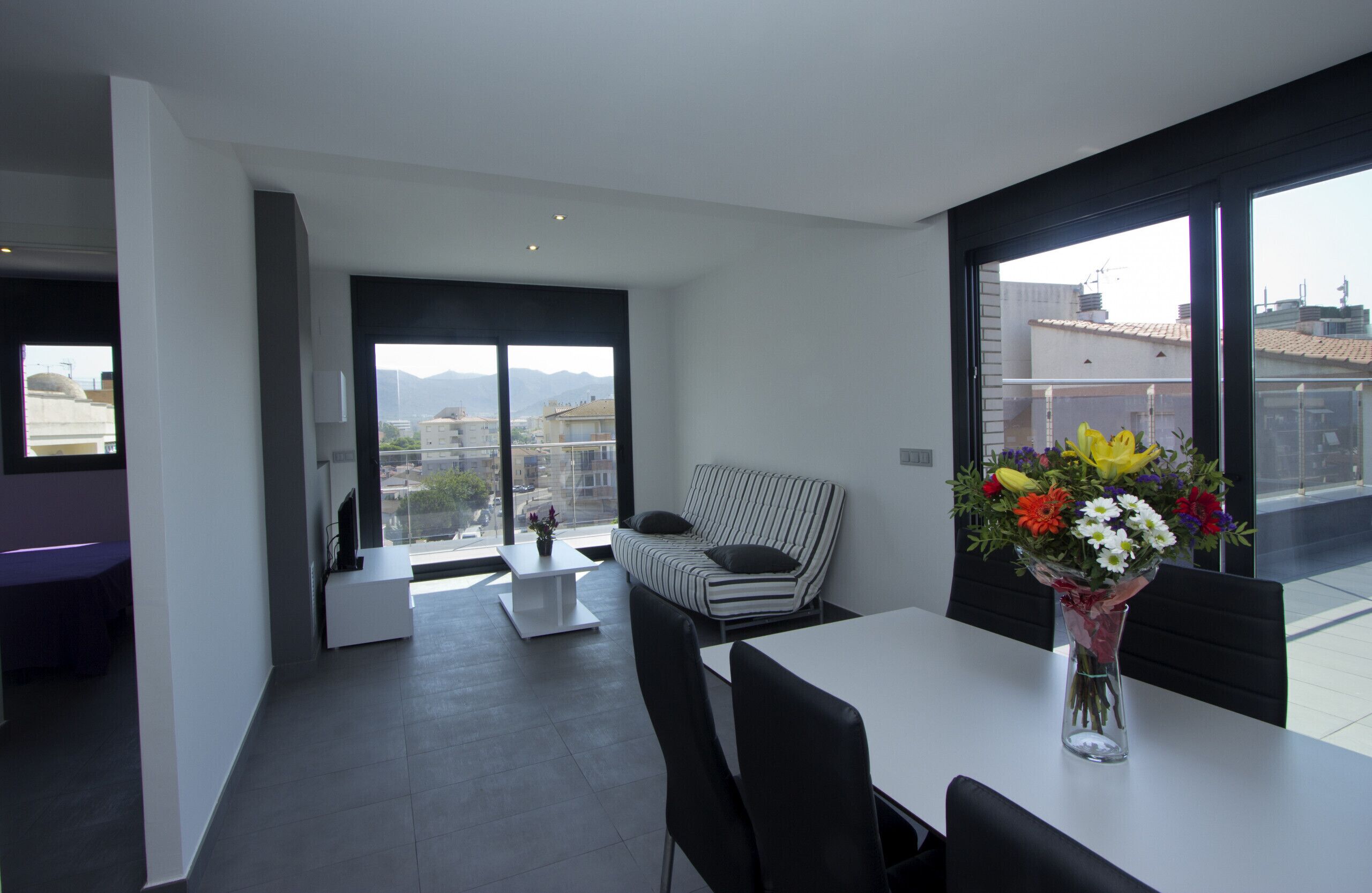 A modern living room with a sofa, a dining table, and a vase of flowers.