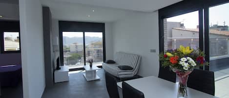 Una sala de estar moderna con un sofá, una mesa de comedor y un jarrón de flores.