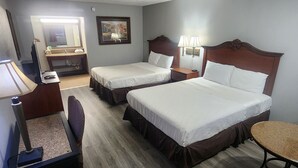 Habitación de hotel con dos camas, un escritorio, una silla, una mesita y un espejo.