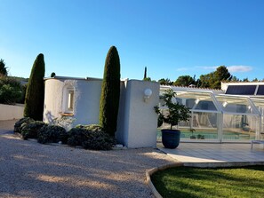 Un petit bâtiment moderne avec une allée en gravier, un pot de fleurs et une serre.