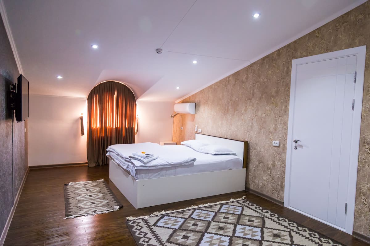 Ein Schlafzimmer mit einem Bett, einem gemusterten Teppich, einer Wandlampe und einer Tür.