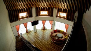 A spacious room with a wooden ceiling, a sofa set, and a flat-screen TV. - MANIJA Hostel (Samarkand)