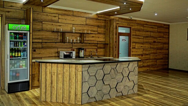 A kitchen with wooden paneling, a refrigerator, a microwave, and a sink. - MANIJA Hostel (Samarkand)