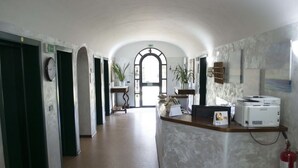 A hotel lobby with a reception desk, a fire extinguisher, and a view of the lobby area. - Nuovo Hotel Sporting (Campagnola Emilia)