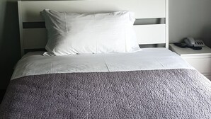 A neatly made bed with a grey quilt, a white headboard, and a wall-mounted artwork of abstract floral designs. - Nuovo Hotel Sporting (Campagnola Emilia)