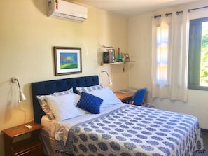 Une chambre à coucher avec un lit, des tables de chevet, un bureau et une fenêtre avec des rideaux.