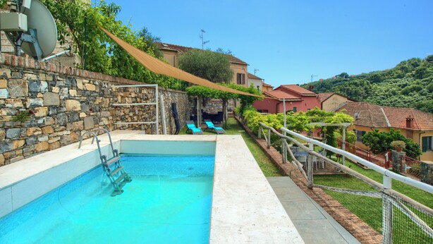 Ein Pool mit Steinmauer, einer Leiter und einem schattigen Bereich.