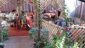 Un espace de restauration en plein air, avec des tables et des chaises, entouré d’une structure en treillis de bambou.