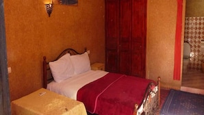 Une chambre à coucher comprenant un lit, une table de chevet, une armoire et donnant sur l’extérieur.