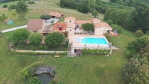 Un'ampia casa circondata da un prato curato e alberi, con una piscina.