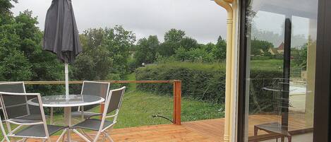 Una terraza de madera con un ventanal de vidrio que da a un patio.