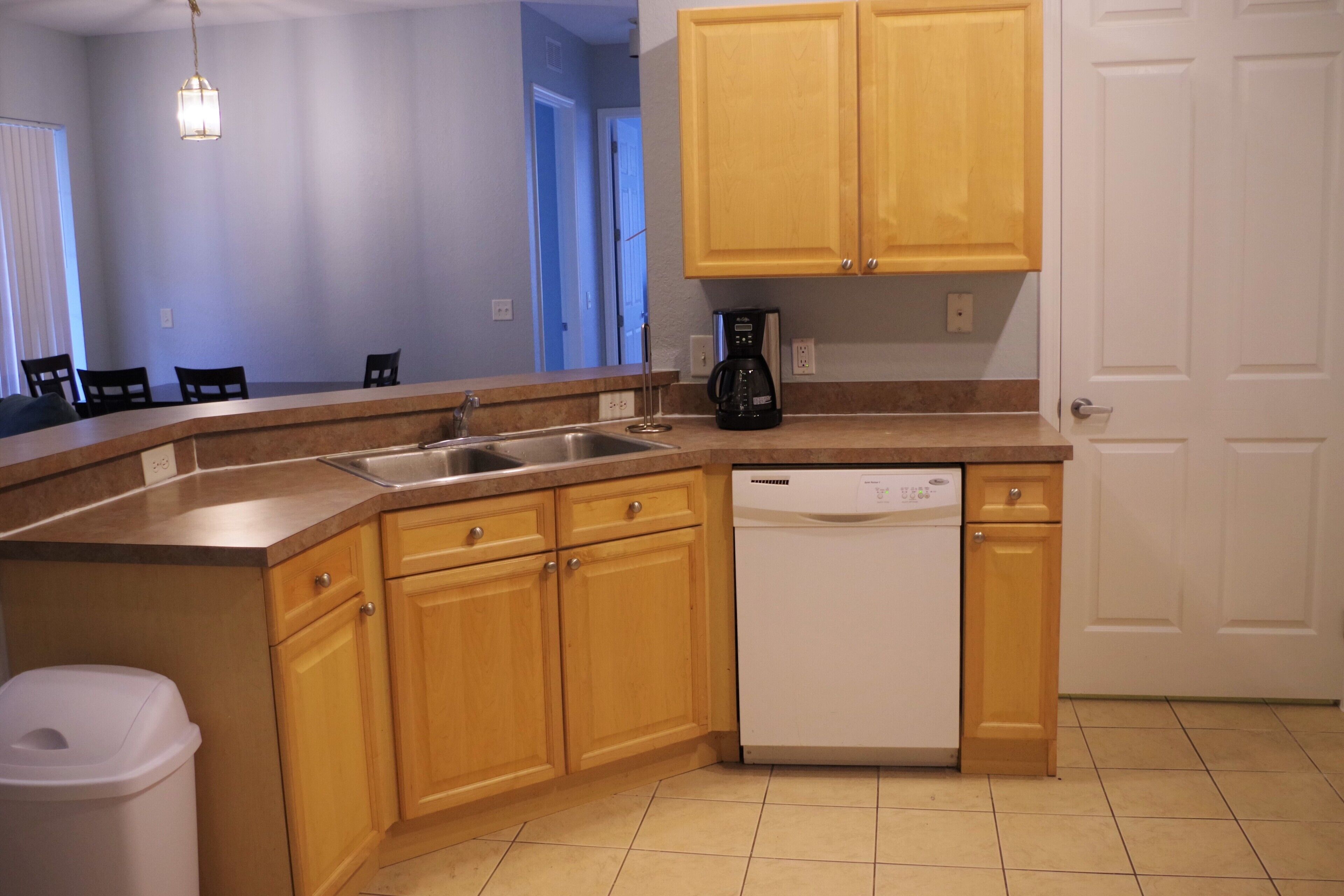 A kitchen with wooden cabinets, a dishwasher, a coffee maker, and a sink.
