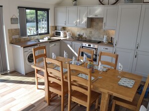 A compact kitchen with a dining area, a washing machine, and a view of the outdoors.