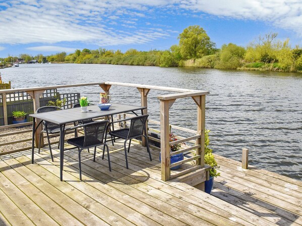 A wooden deck with a table and chairs overlooking a river.