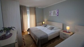 Ein Hotelzimmer mit einem Bett, Nachttischen, einem Schreibtisch und einem Fenster mit Vorhängen.