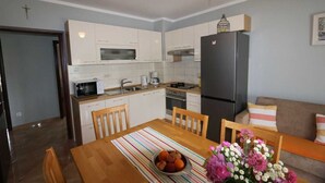 Eine moderne Küche mit weißen Schränken, einem schwarzen Kühlschrank und einem Esstisch mit Stühlen.