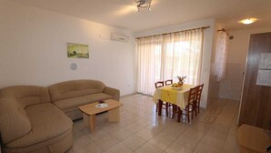 A living room with a sofa, a small table, a dining table with chairs, a window with curtains, and a door. - Apartment Dudovic Damir A2 nr 1 (Silo - island Krk)