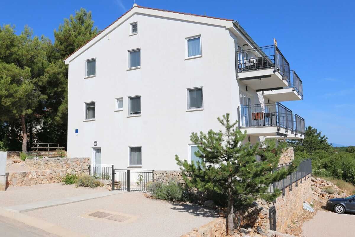 Un immeuble à plusieurs étages, doté de balcons et d’une façade en pierre, sous un ciel dégagé.