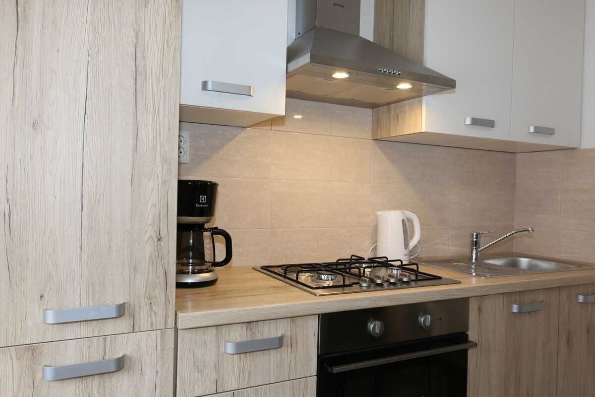 A modern kitchen with a gas stove, coffee maker, and a built-in oven.