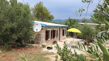 A stone building with a satellite dish, a yellow umbrella, and a view of mountains in the background.