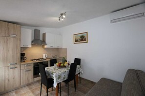 A compact kitchen with a dining area, a sofa, and a painting on the wall.