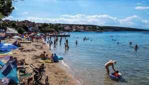 A beach with people swimming and sunbathing, tents, and a clear sky. - House Car Mirko (Silo - island Krk)