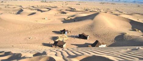 Paisaje desértico con dunas de arena y tiendas de campaña.