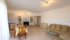 A living room with a sofa, a glass coffee table, and a dining area with chairs and a table. - Apartment Dudovic Darko nr 3 (Silo - island Krk)
