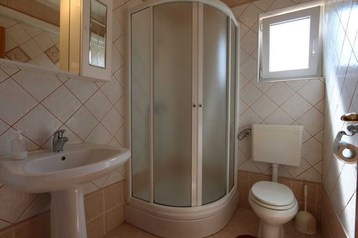 A bathroom with a shower, sink, toilet, and a window.