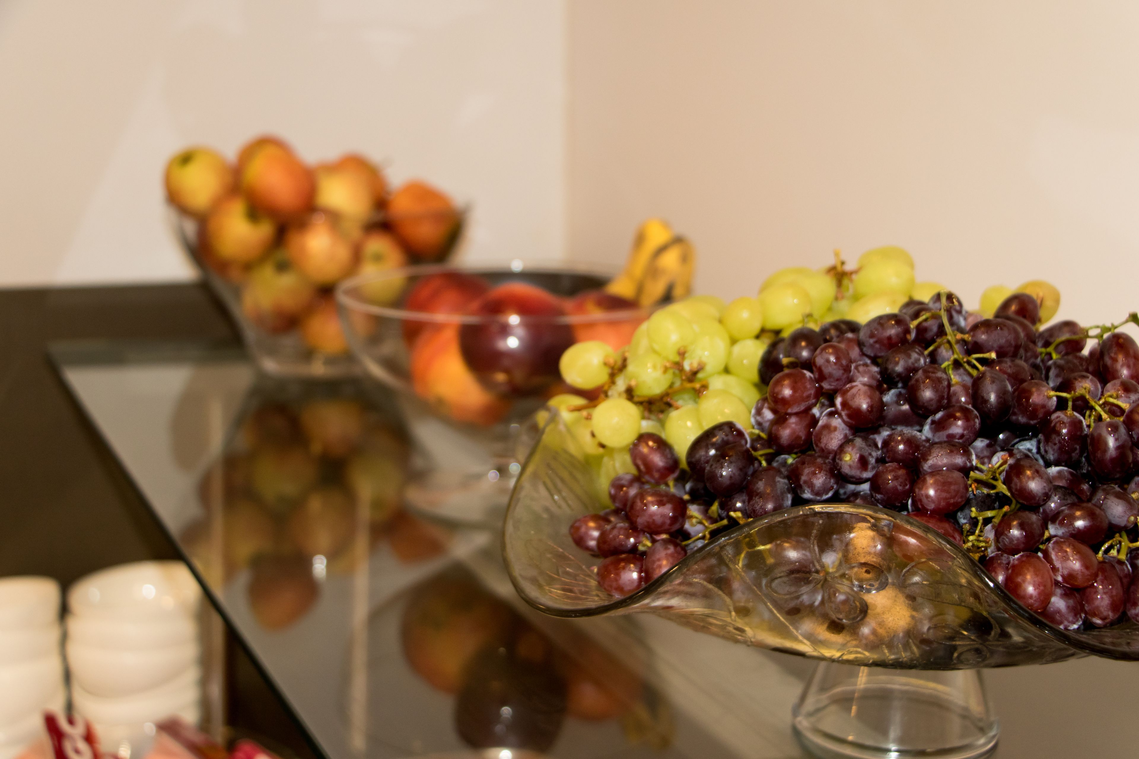 A table with three glass bowls containing various fruits.