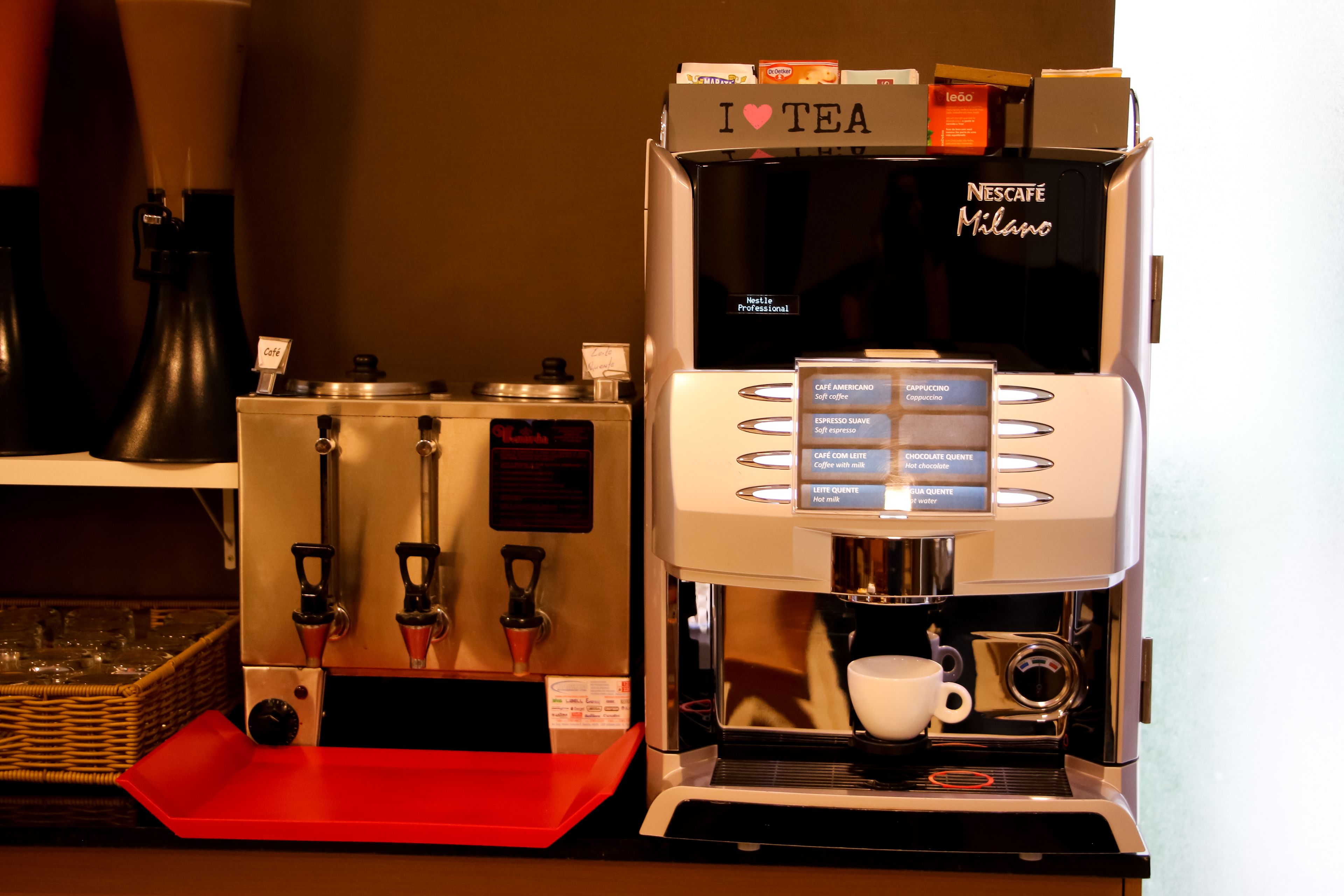 Una máquina de café espresso Nescafe Milano con un portavasos y una pantalla de menú.