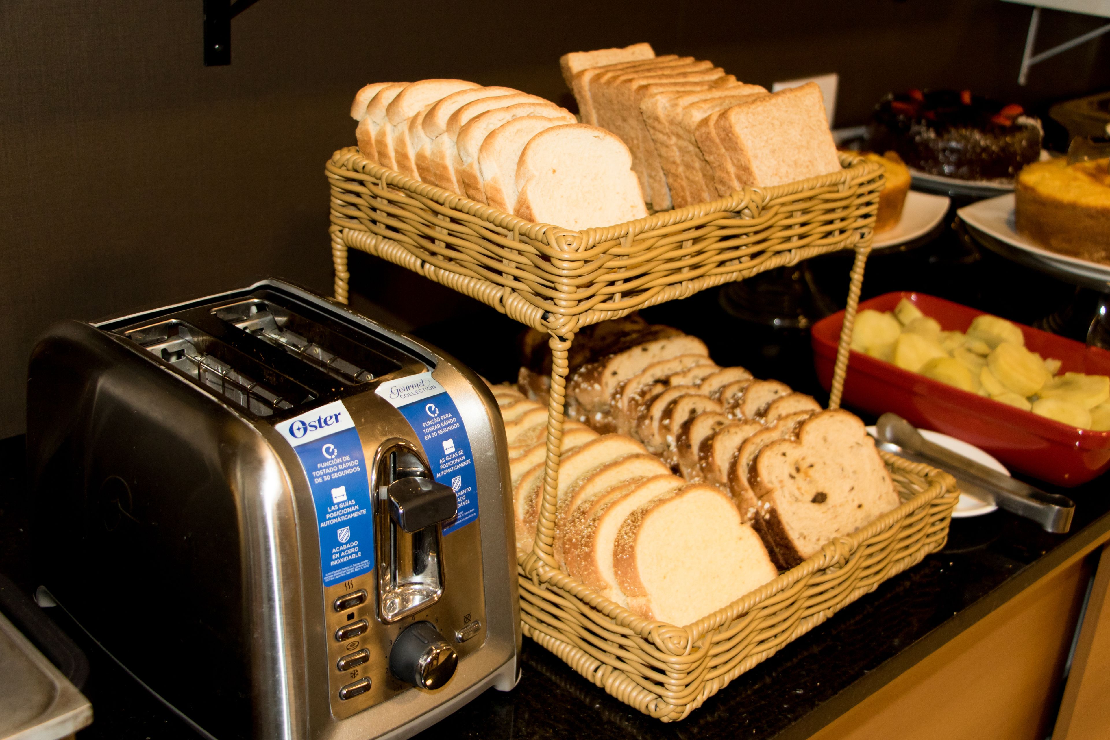 A toaster and two wicker baskets filled with sliced bread on a counter.